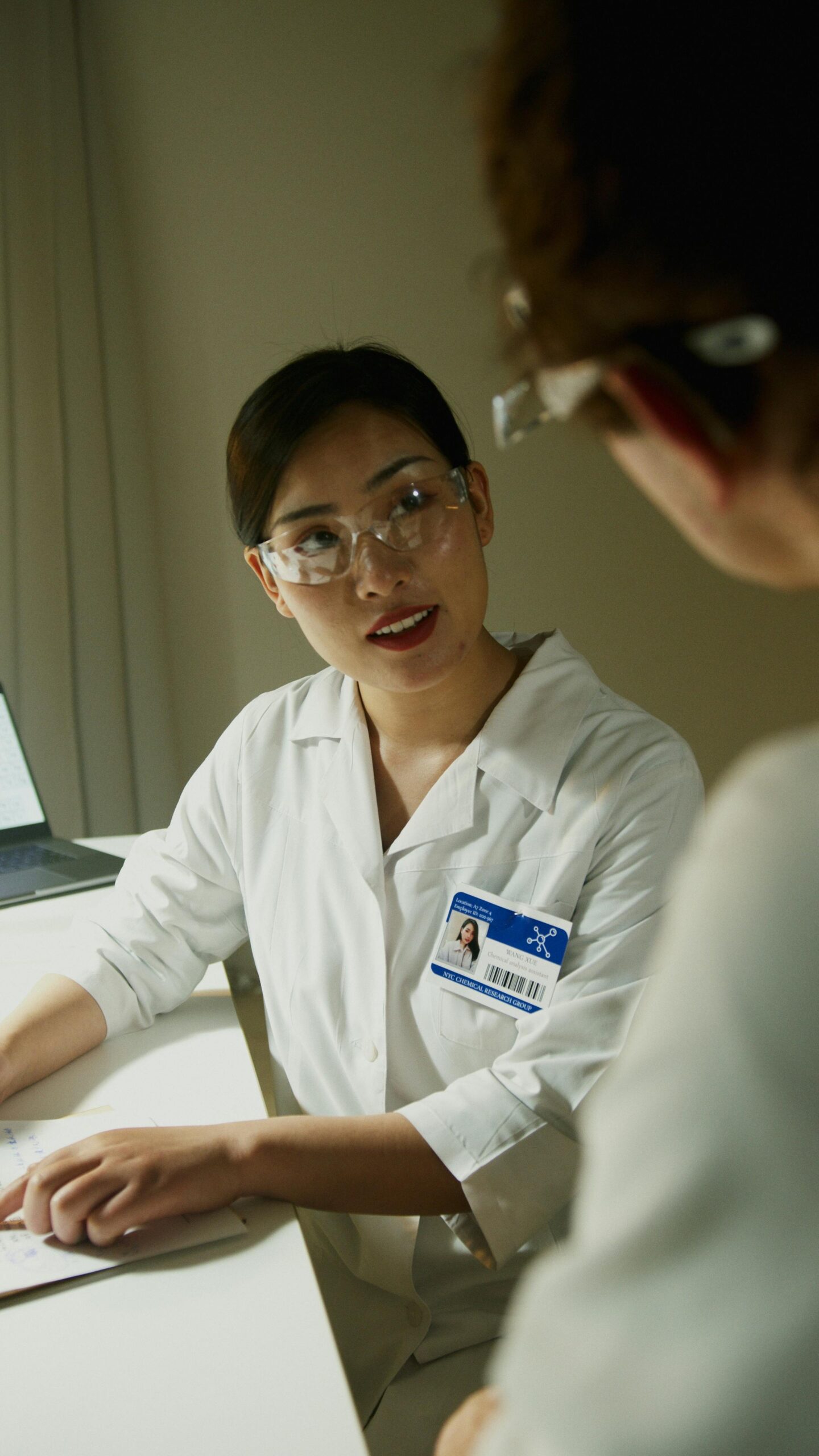 A female scientist wearing a lab coat and goggles in a laboratory environment.